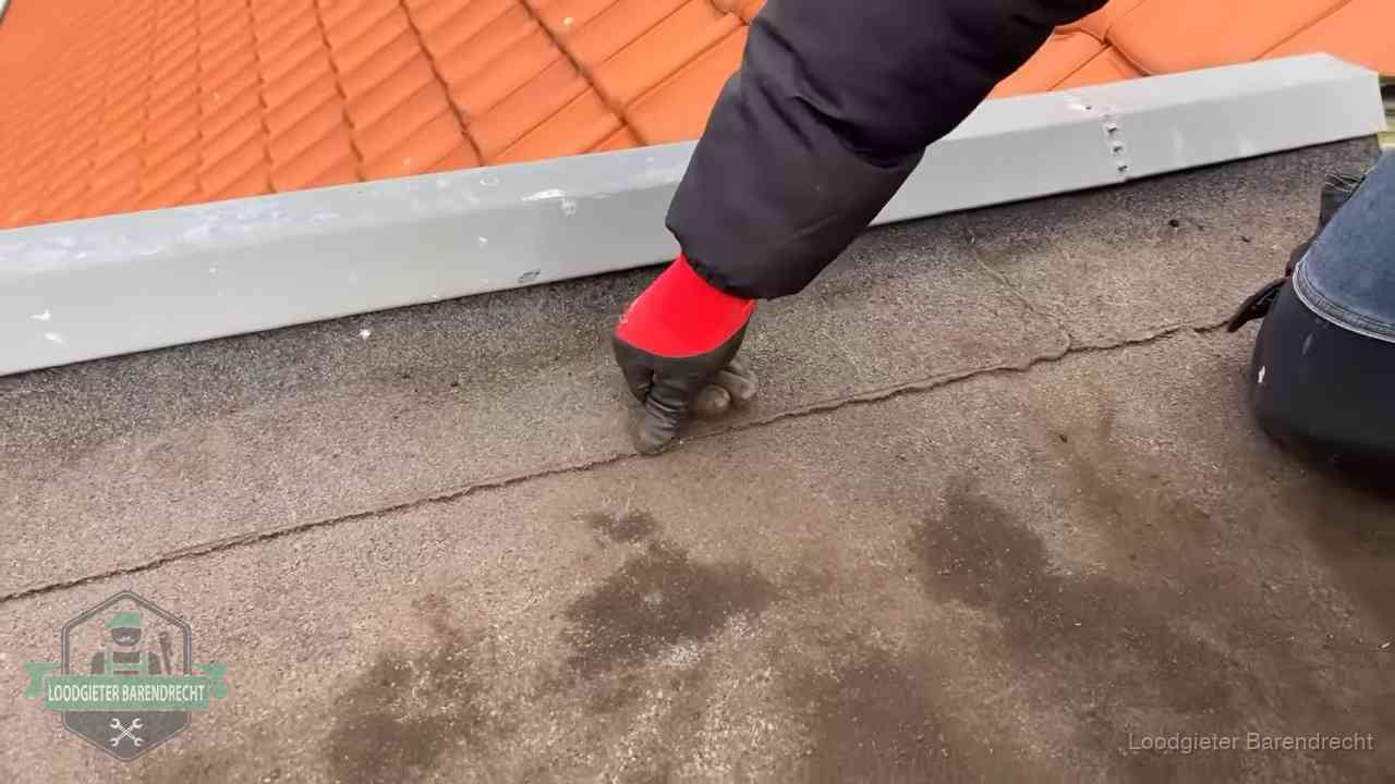 Lekkage bij de naad van een plat dak in Barendrecht Vakman wijst een naad met vochtplekken aan op een bitumen plat dak in Barendrecht