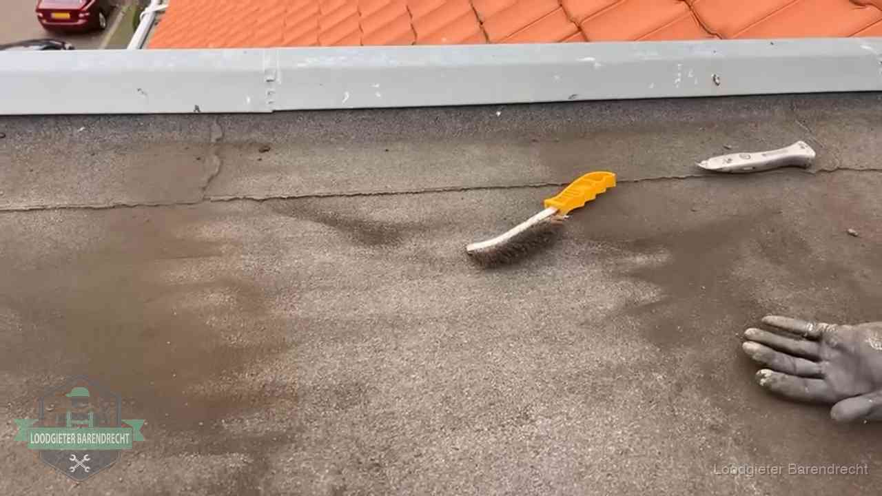 Kosten van daklekkage-reparatie in Barendrecht Dakdekker bereidt een bitumen plat dak voor op reparatie bij de daktrim in Barendrecht