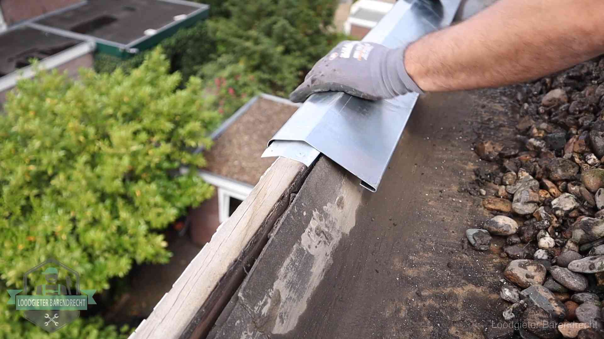 Daklekkage per wijk in Barendrecht Dakdekker plaatst een zinken deklijst op een dakrand met uitzicht over een woonwijk in Barendrecht