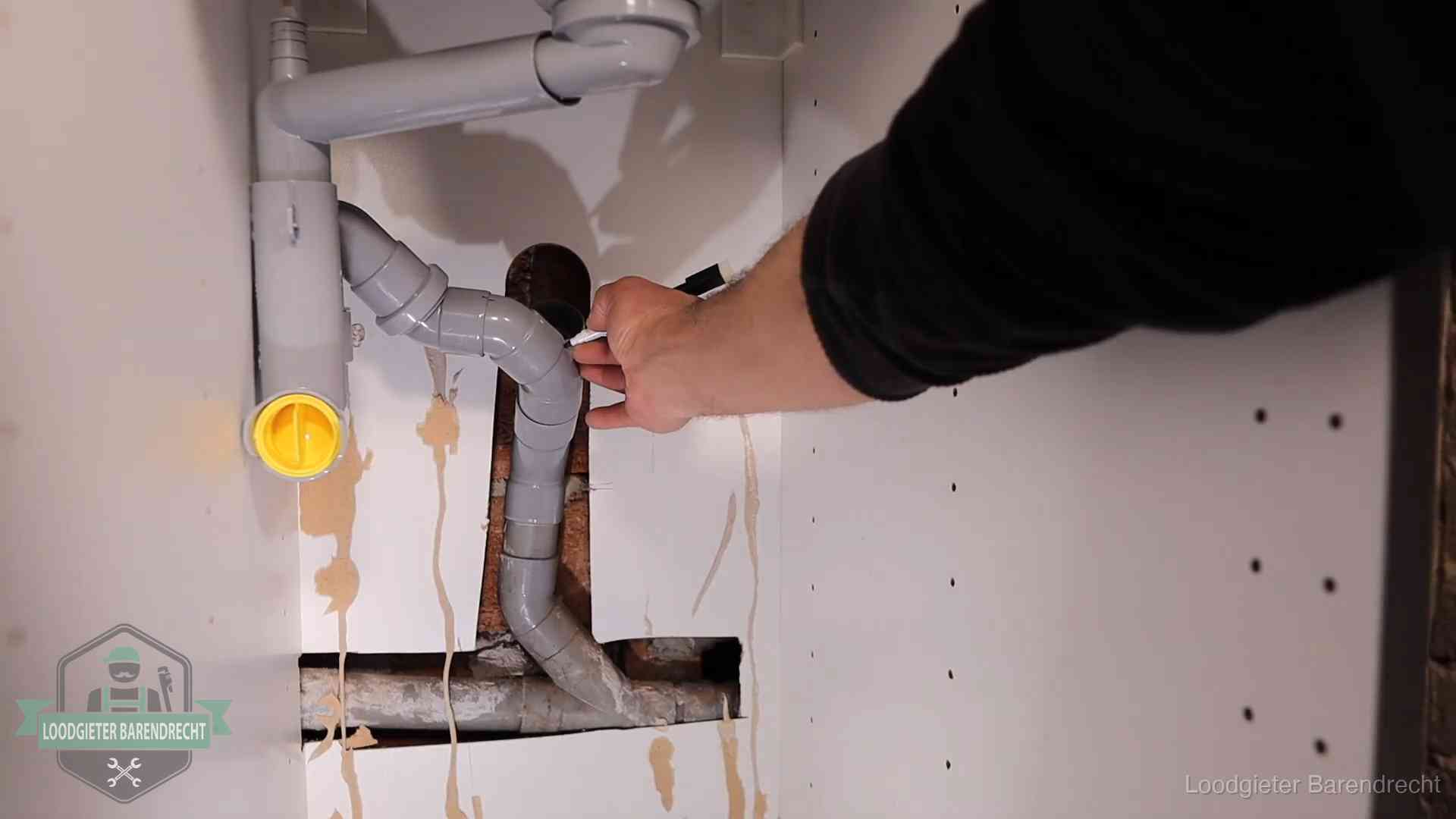 Loodgieter markeert een pvc-afvoerbuis onder een gootsteen in Barendrecht