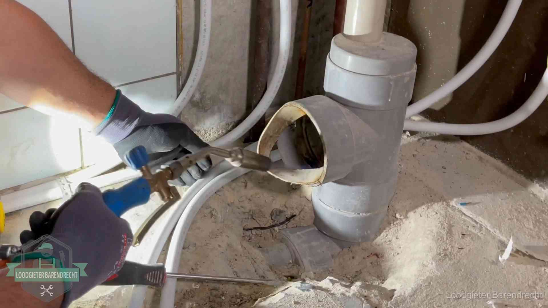 Loodgieter werkt met brander en messing kraanwerk aan leidingen in Barendrecht