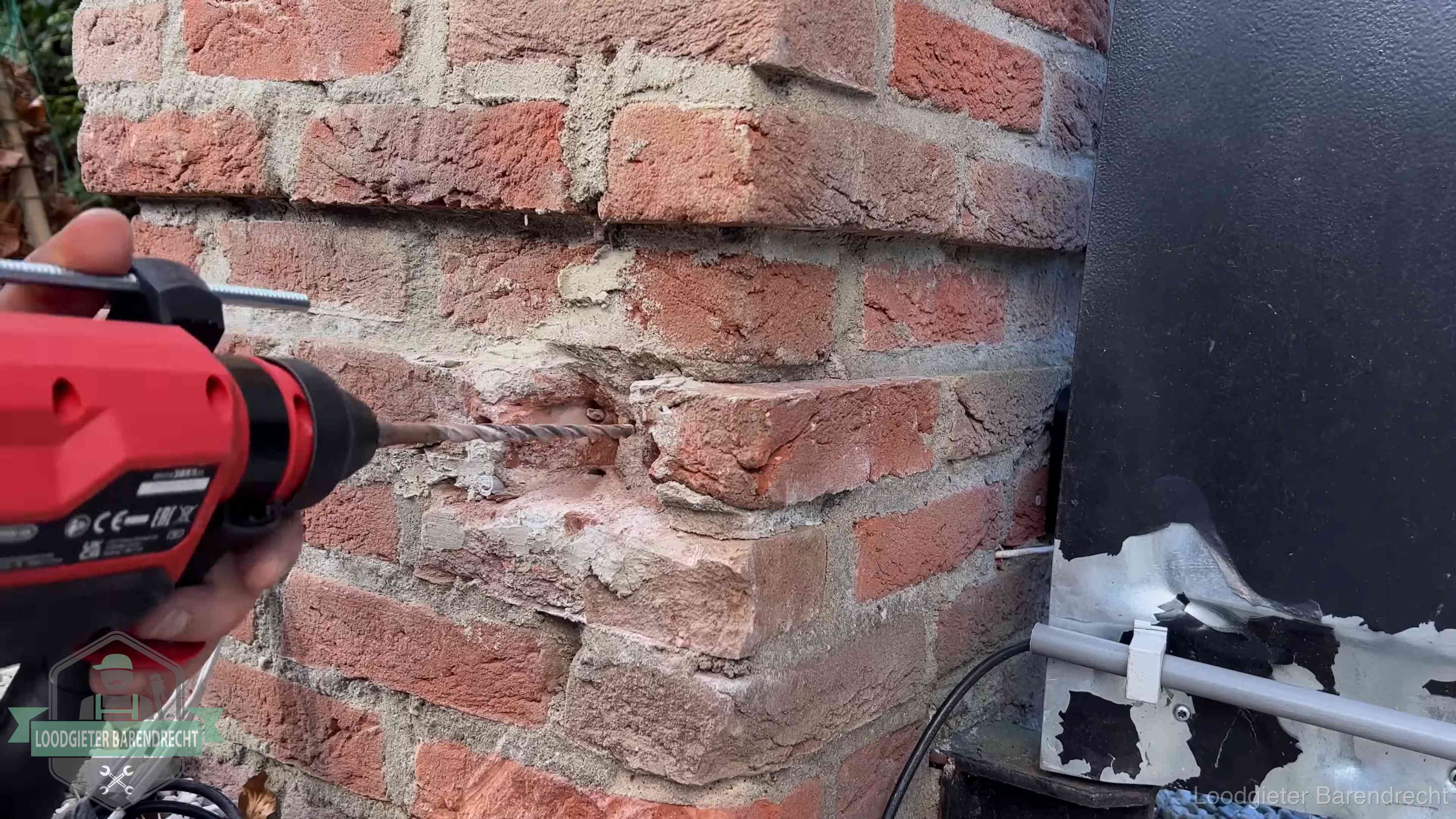 Vakman boort in de buitenmuur van een woning in de regio Barendrecht