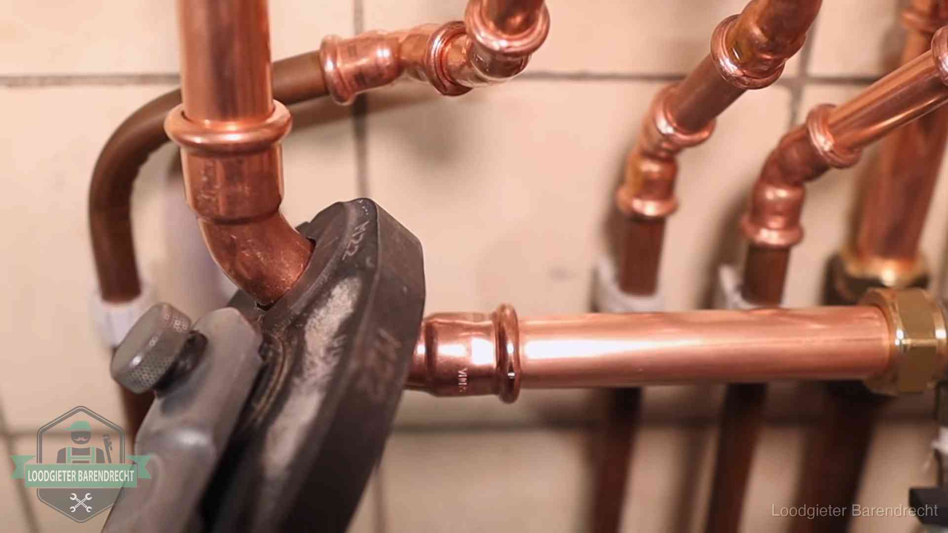 Persmachine perst een koperen fitting op nieuw leidingwerk in Barendrecht