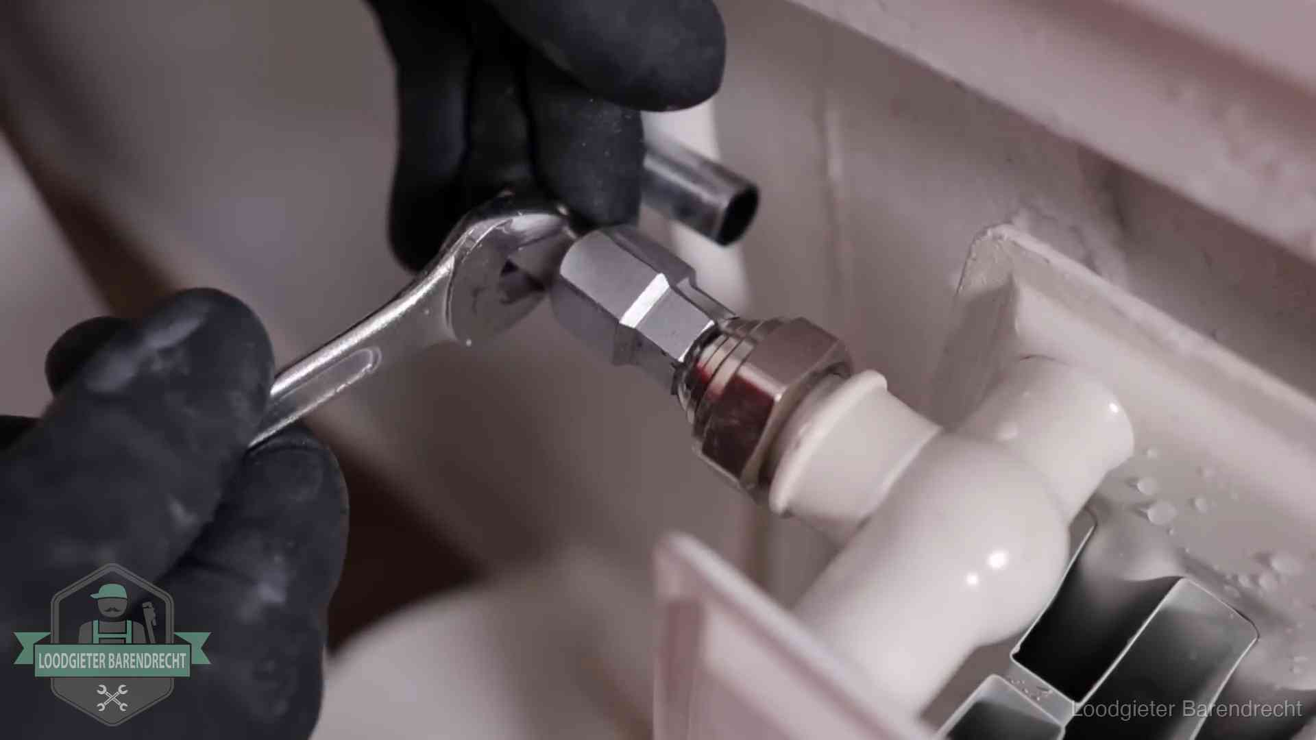 Steeksleutel draait een wartelkoppeling op een radiatorkraan aan in Barendrecht