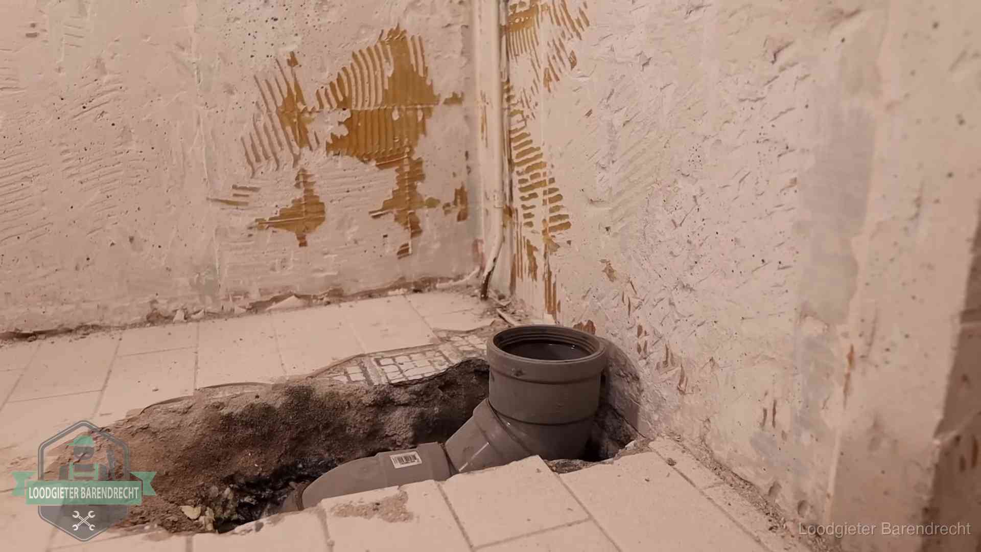 Verzakt riool herstellen in Barendrecht Opengebroken vloer met een nieuwe pvc-rioolbocht in een gegraven sleuf in Barendrecht