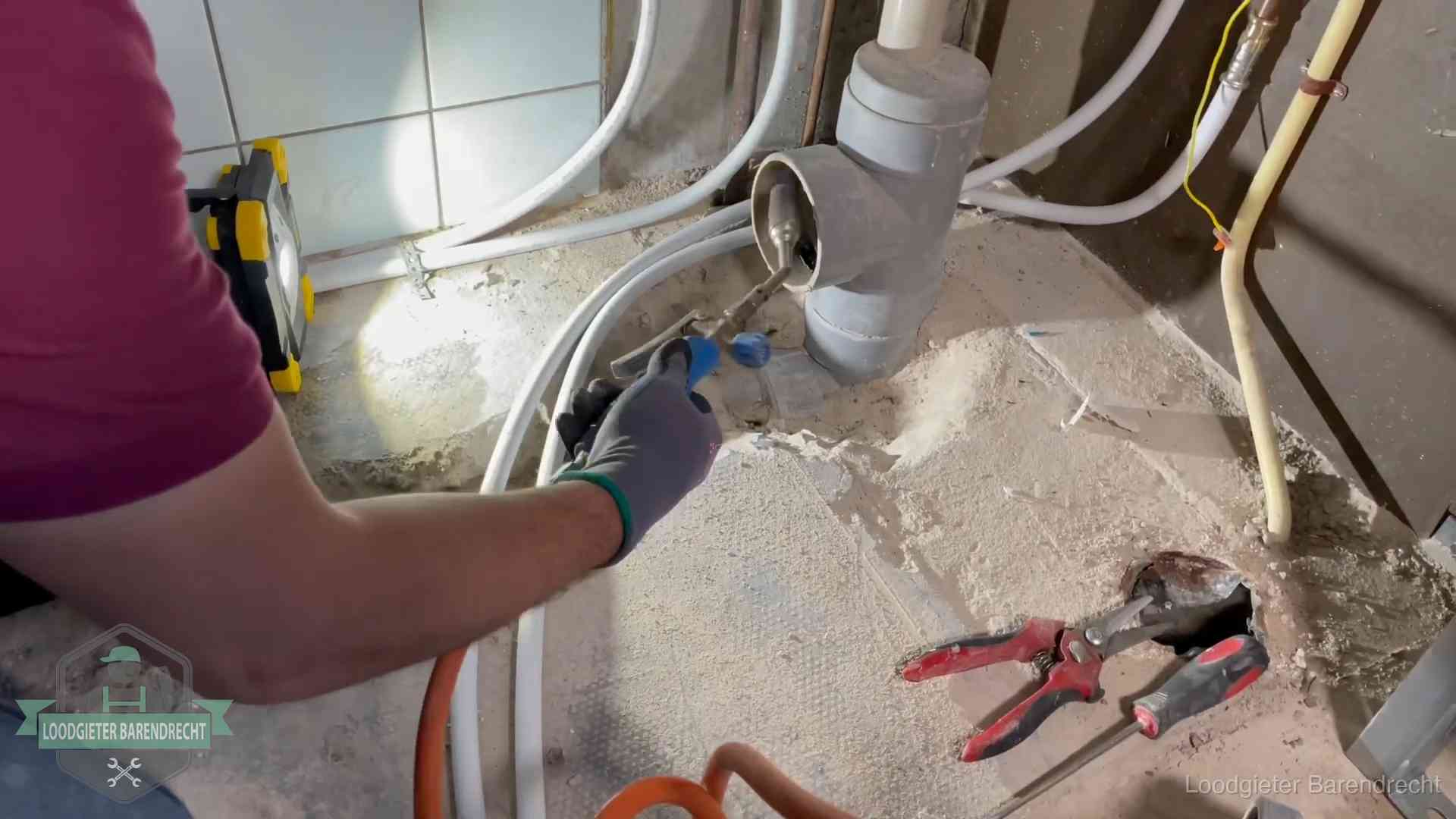 Loodgieter werkt aan leidingen bij een pvc-standleiding in een appartement in Barendrecht